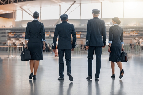 two pilots and two flight attendants in uniform walking through airport terminal